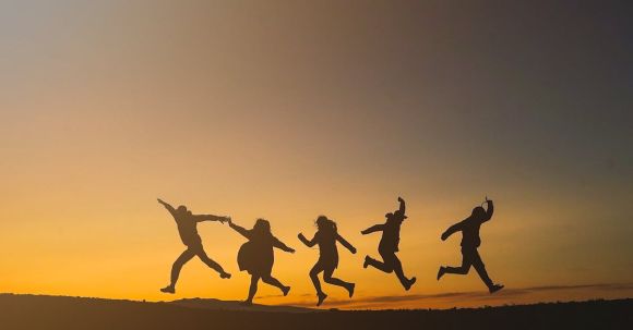 Group Dynamics - Unrecognizable happy people jumping in sunset
